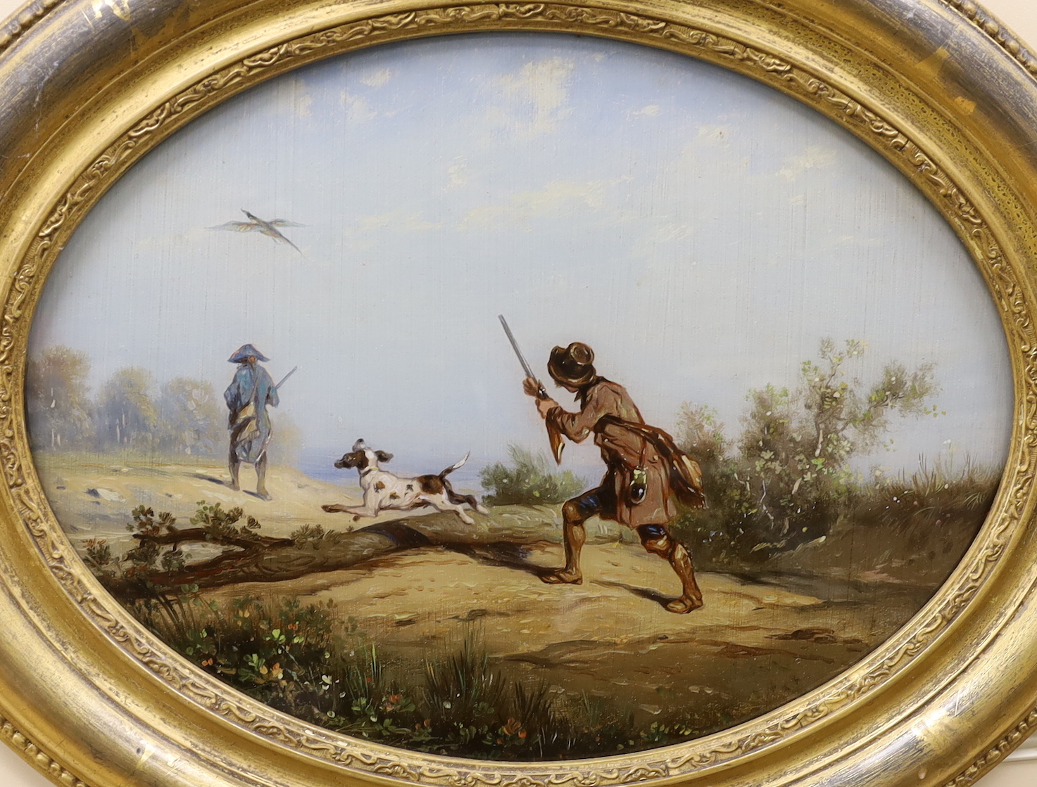 A pair of 19th century reverse painted oval framed sporting scenes, figures shooting along a pathway, 23 x 31cm